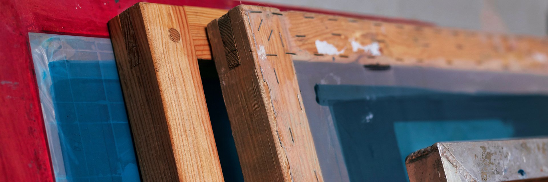 Fyra ramar, en röd, två träfärgade och en av metall som står lutade mot en vägg.